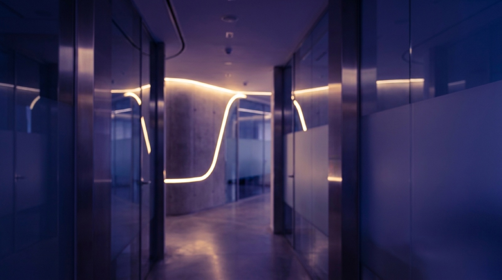 Modern clinic architecture at night with one warm gold light line through violet dusk
