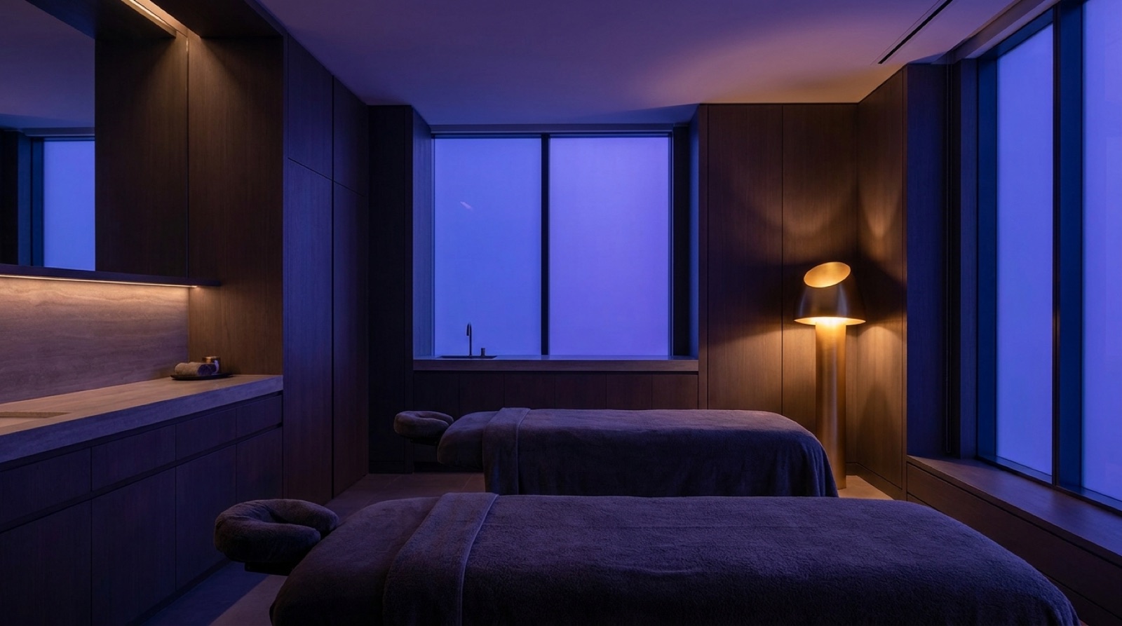 Premium med spa treatment room in violet dusk light with a warm gold accent lamp